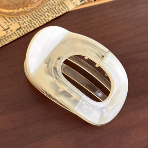Detailed view of large cream marble claw clip with hollow oval design on wood surface