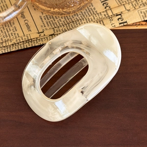 Detail view of oval cream marble hair claw clip on a rustic wood background