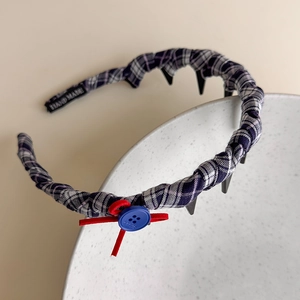 Close-up of British style plaid headband with red bow, blue button and non-slip teeth