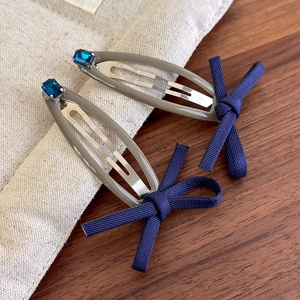 Vintage denim blue bow hair clips with navy rhinestones on rustic wooden background