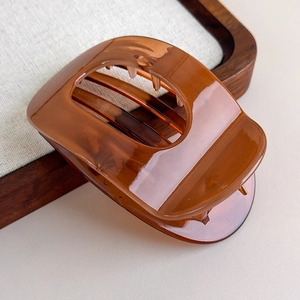 Macro shot of large amber resin hair claw clip with glossy finish and curved teeth