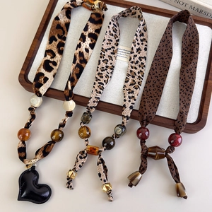 Retro leopard print beaded scarf necklace with heart pendant on a wooden display tray