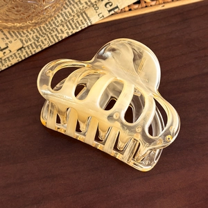 Close-up of translucent amber hair claw clip with vintage texture on a wooden desk