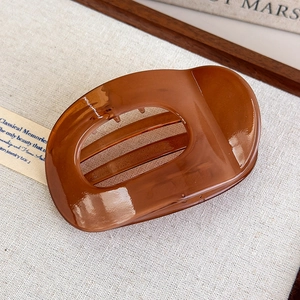 Detail of an amber acetate hair claw clip with cutout design on beige fabric