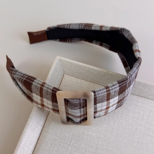 Close-up of a wide padded plaid headband with a brown marble resin buckle detail