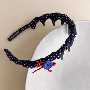 Detail view of navy polka dot headband featuring a red bow and anti-slip teeth design