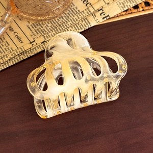 Detail of amber translucent hair claw clip with geometric resin texture on vintage paper