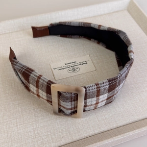 Detail showing the brown plaid fabric texture and marbled resin buckle on the headband