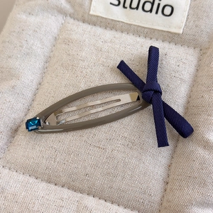 Detailed macro view of vintage denim bow hair clip with dark blue rhinestone accents