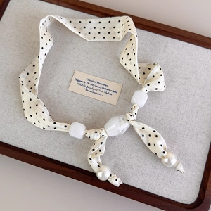 Dettaglio della collana foulard in seta a pois con grandi perle bianche sfaccettate