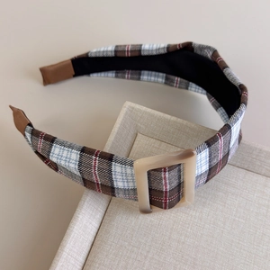 Detail of vintage brown plaid headband with a square buckle on a beige tray