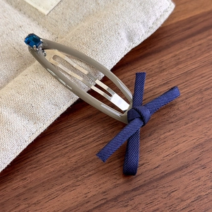 Detailed shot of a vintage denim bow hair clip with a navy rhinestone on an alloy BB clip
