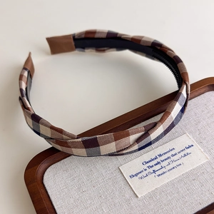 Nahaufnahme eines Retro-Plaid-Stirnbands mit rutschfesten Zähnen auf einem Holztablett