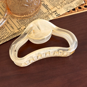 Detail of a creamy yellow heart-shaped hair claw on a vintage wooden surface