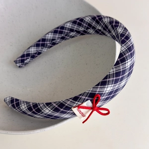 Detailed view of British plaid headband featuring a delicate red bow and handmade label