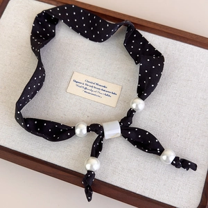 Dettaglio della collana in tessuto a pois con perle e cursore effetto marmo bianco