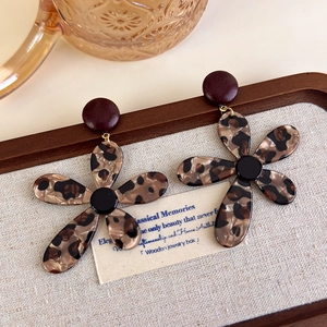 Detailed close-up of leopard print flower earrings with acrylic petals on a linen tray