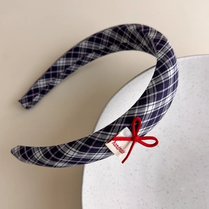 Detail view of plaid headband with red velvet bow and handmade label accent