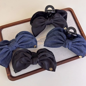 Détail de pinces à cheveux en denim et satin avec breloques dorées sur un plateau