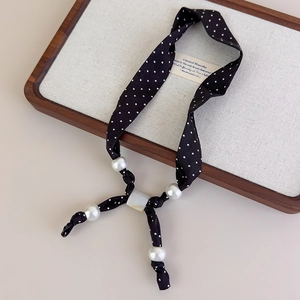 Dettaglio della collana foulard in seta a pois con grandi perle bianche e una perla gialla