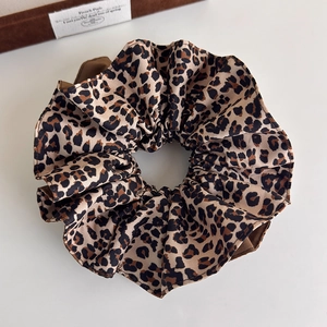 Gros plan d'un chouchou en satin imprimé léopard avec tissu plissé élégant et tons bruns