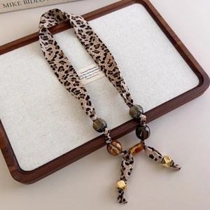 Detail of leopard print fabric necklace with amber resin beads and golden accents