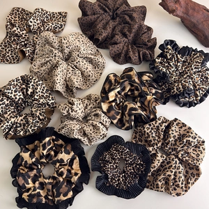 Various leopard print scrunchies in brown and beige tones laid on a minimalist background