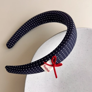 Detail of navy polka dot sponge headband with red bow and handmade textile label