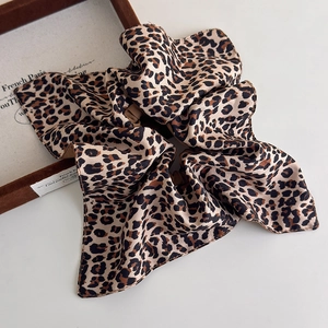 Détail d'un chouchou en satin à motif léopard marron avec texture soyeuse et brillante