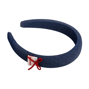 Detail of dark blue denim headband with handmade label and delicate red bow decoration