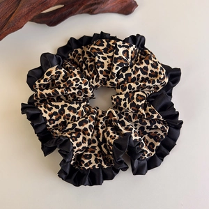 Detailed view of leopard print scrunchie with black ruffled edges and silky texture