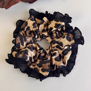 Detail of leopard print satin scrunchie featuring elegant black pleated ruffle edges