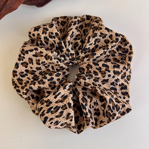 Detailed close-up of leopard print scrunchie with soft fabric texture and pleated design