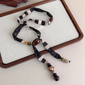 Detail of bohemian silk scarf necklace with leopard print beads and tiger eye stone