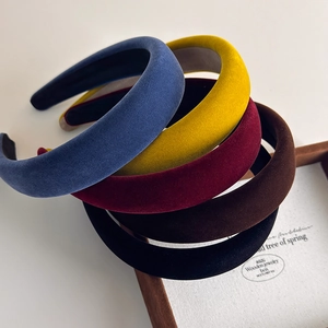 Detail showing stacked thick velvet headbands in deep blue, yellow, red, coffee, and black