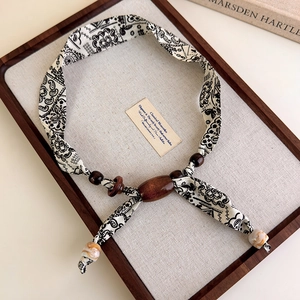 Detail of leopard print fabric necklace with wooden beads and paisley pattern textile