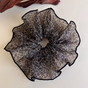 Close-up of leopard print hair scrunchie made of light semi-transparent chiffon fabric