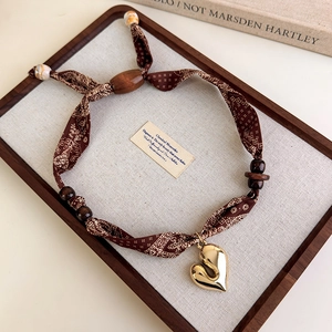 Detail view of vintage leopard scarf necklace with gold heart pendant and wooden beads