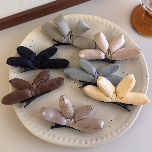 Padded satin bow hair clips in Morandi colors displayed on a ceramic plate