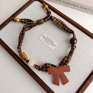 Detail of vintage brown plaid fabric necklace with leopard beads and leather bow charm