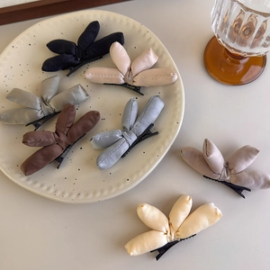 Close-up of padded fabric bow hair clips in various colors displayed on a tray