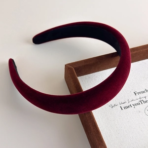 Detail of burgundy velvet padded headband showing thick texture on a display case