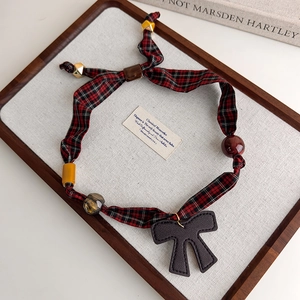 Detail of vintage red plaid fabric necklace with leopard beads and a grey bow pendant