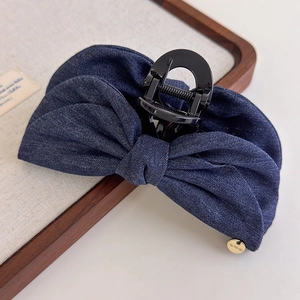 Détail d'une grande pince à cheveux en denim bleu avec pendentif doré en métal