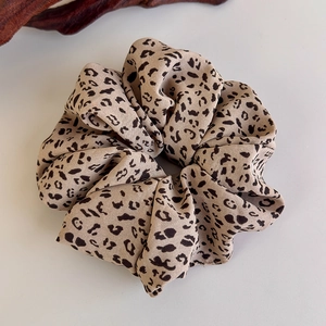 Macro shot of leopard print scrunchie with soft chiffon texture and pleated design