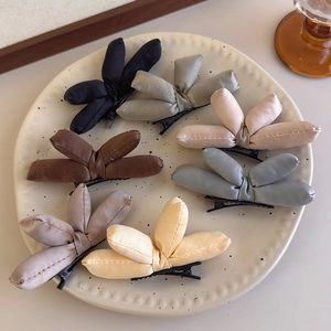 Detail of seven colorful padded fabric bow hair clips arranged in a ceramic polka dot dish