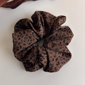 Macro shot of large leopard print scrunchie with soft pleated silk texture on beige base