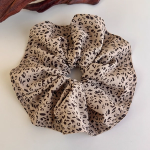 Detailed close-up of leopard print scrunchie with soft chiffon texture and folded ruffles