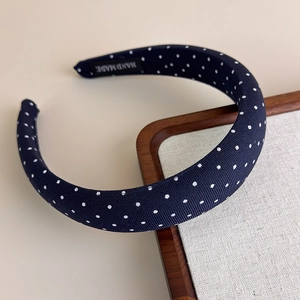 Dettaglio del cerchietto blu navy a pois con tessuto strutturato ed etichetta fatta a mano