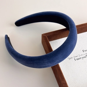 Detailed close-up of dark blue velvet padded headband on a vintage brown display tray